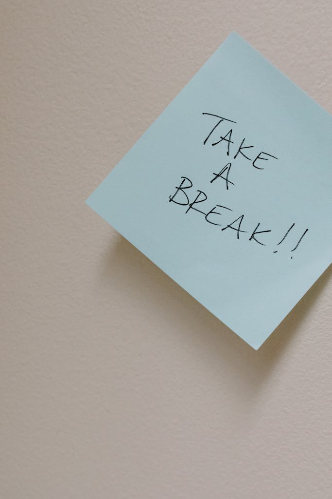 Close-up of a sticky note with 'Take a Break!!' message on a plain wall.